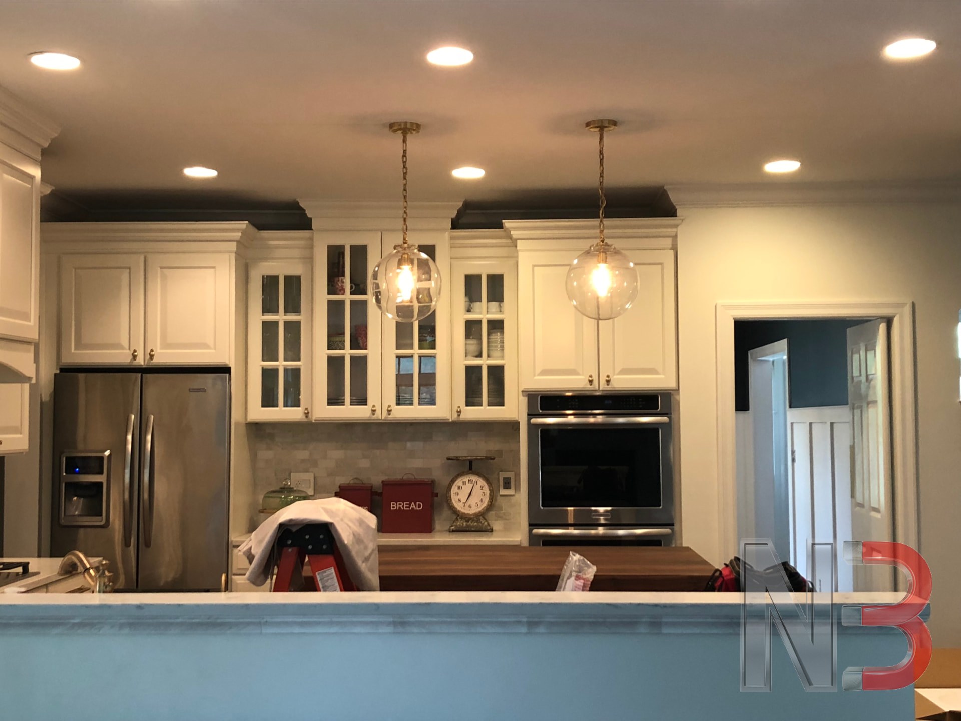 Kitchen with new recessed can lights and glass pendant lights installed over the counter