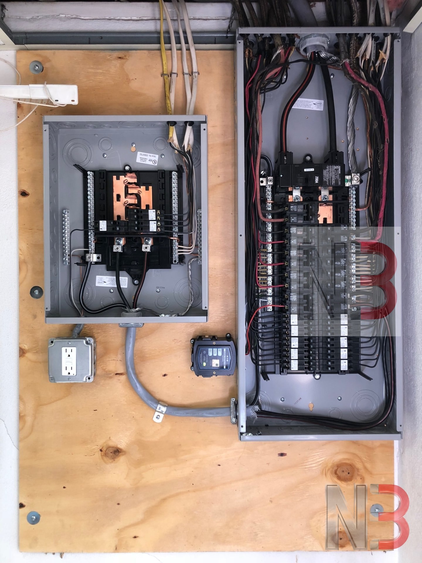 New 200 amp panel and sub panel with whole-home surge protection installed on a plywood backboard